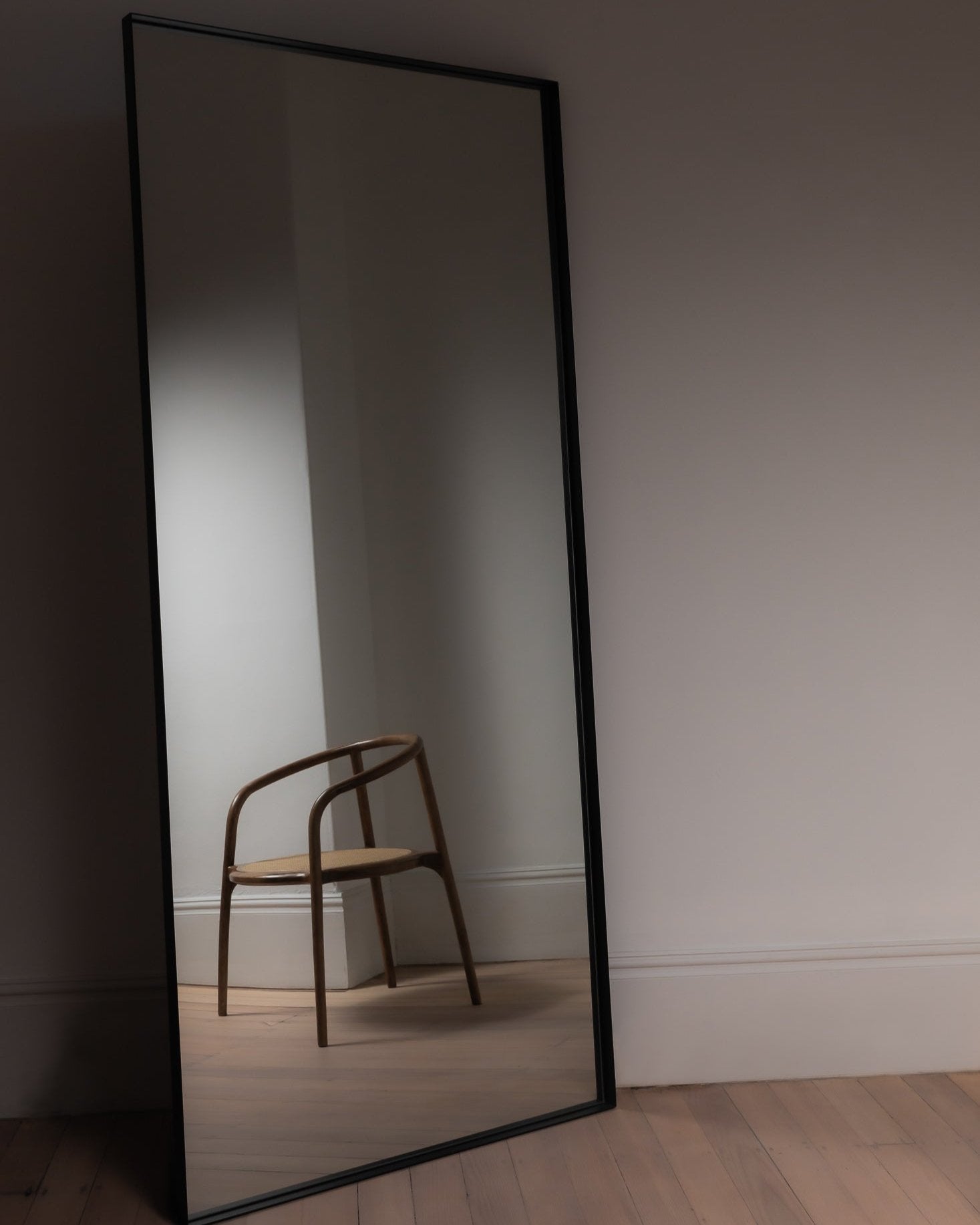 Luca oversized mirror in black styled in a moody space with dark tones and ambient lighting