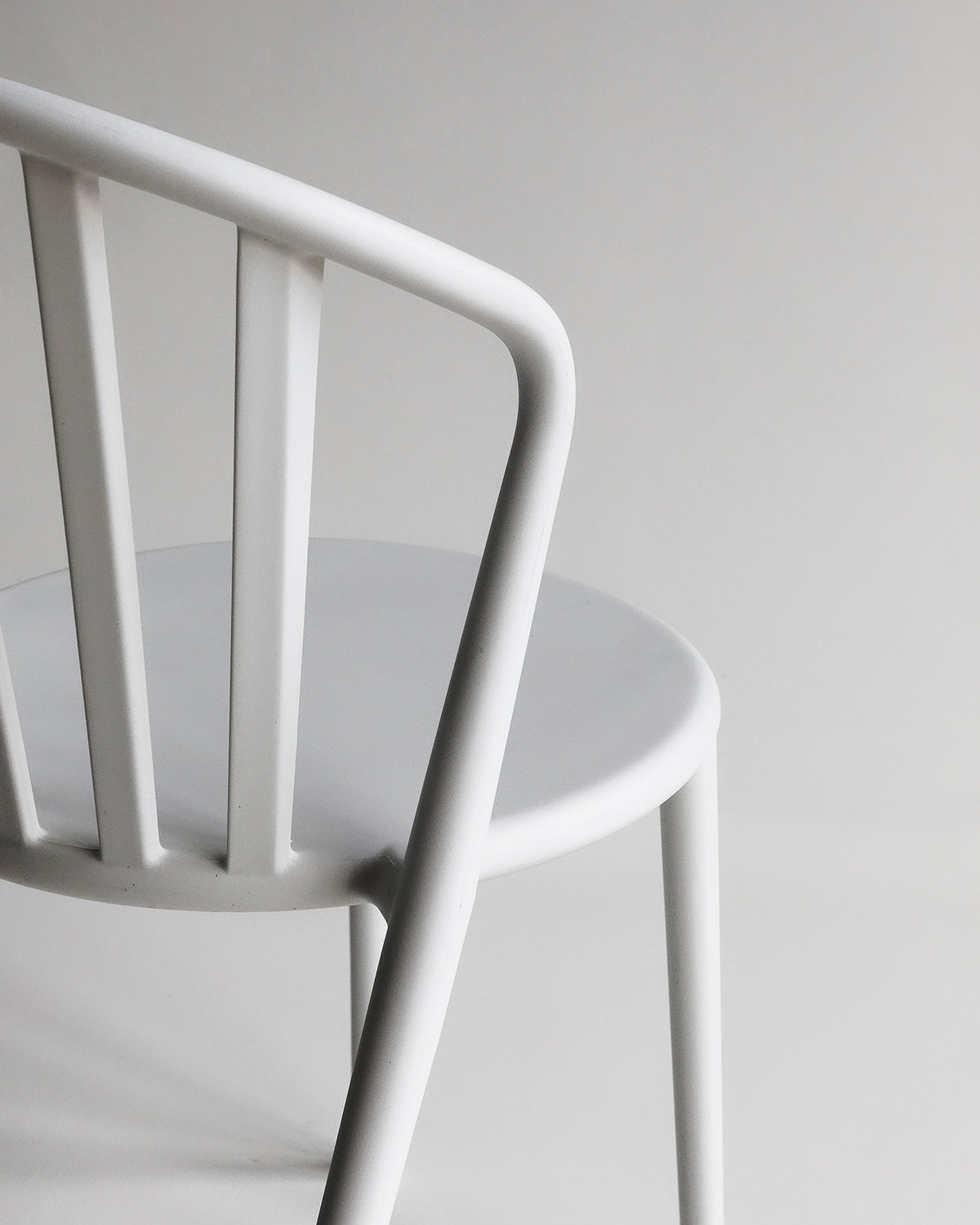 Studio image of the white Cleo dining chair shown from the back, highlighting the smooth, curved backrest and tapered legs