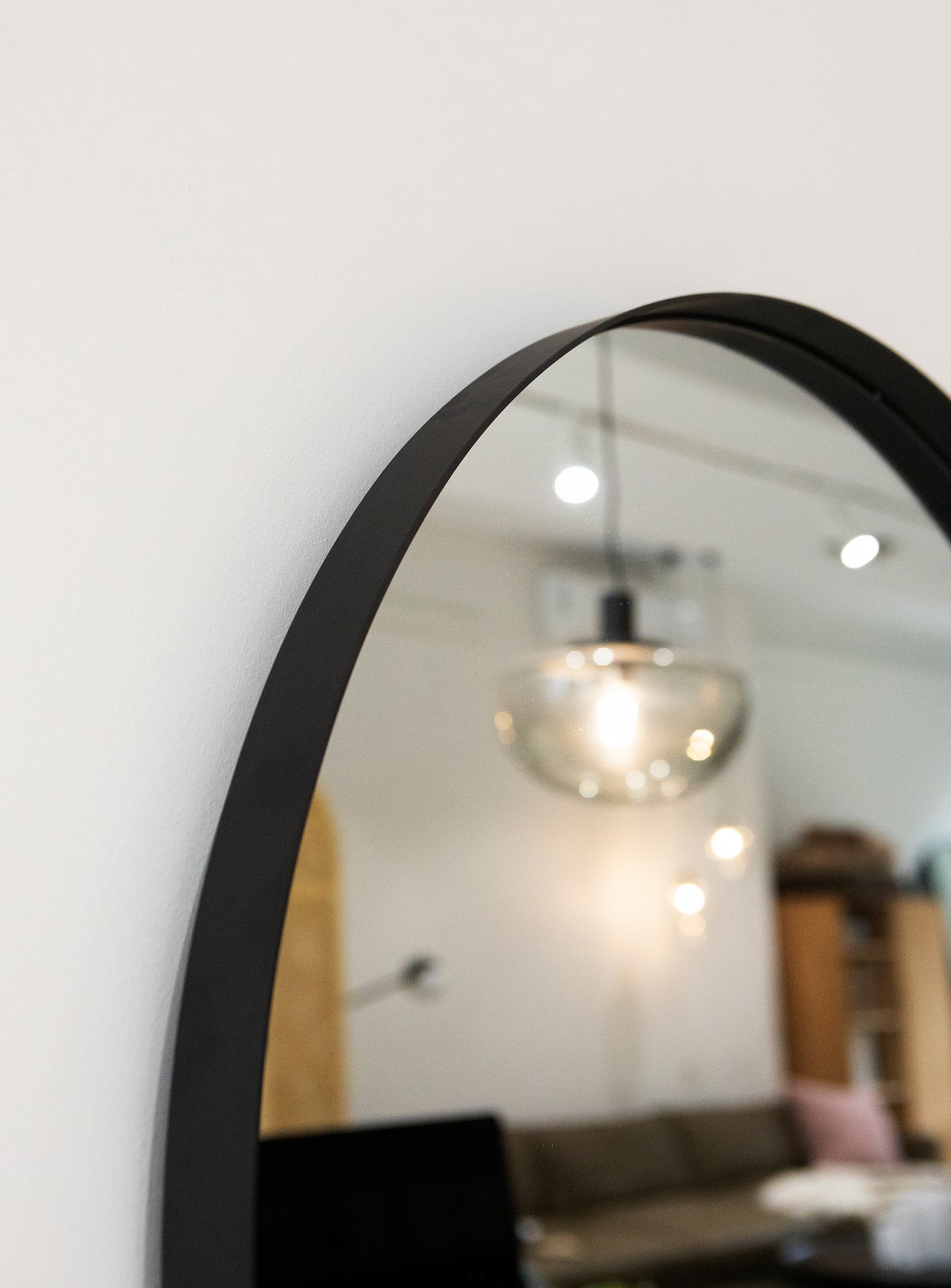 Close-up detail of the slim black powder-coated frame and recessed edge on the Bobbi Round Mirror