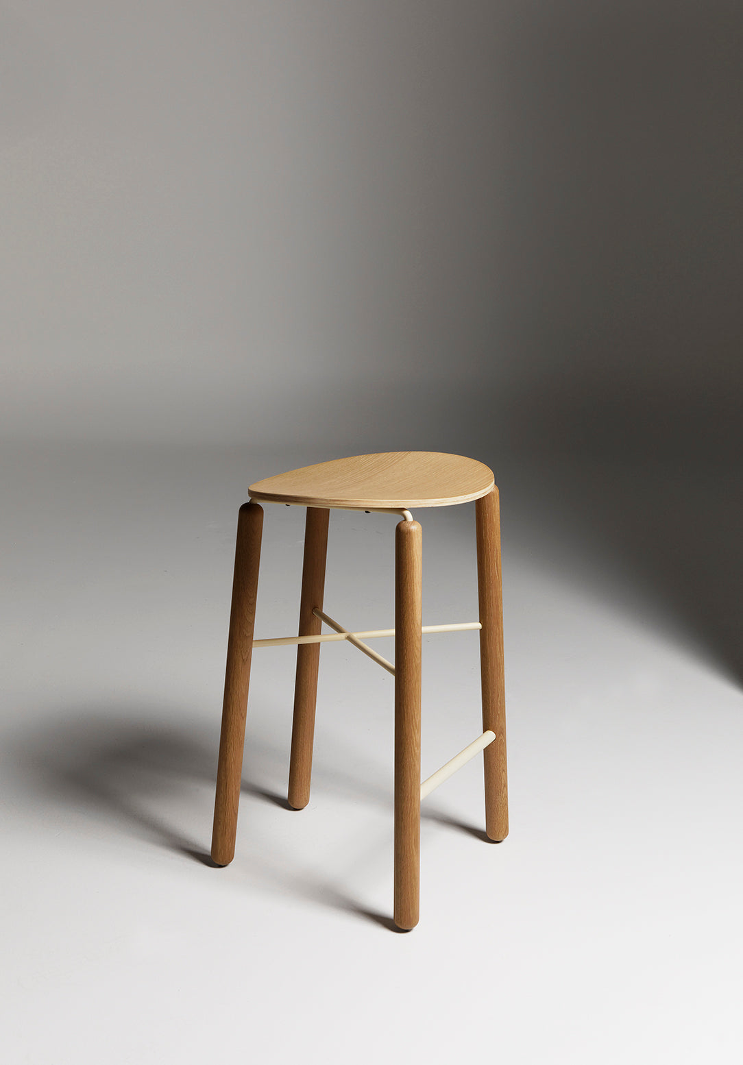 Oak Greta stool shown front-on in a studio setting with light timber seat and slim metal legs