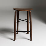 Walnut Greta stool photographed front-on, showing rich timber seat and slim metal base