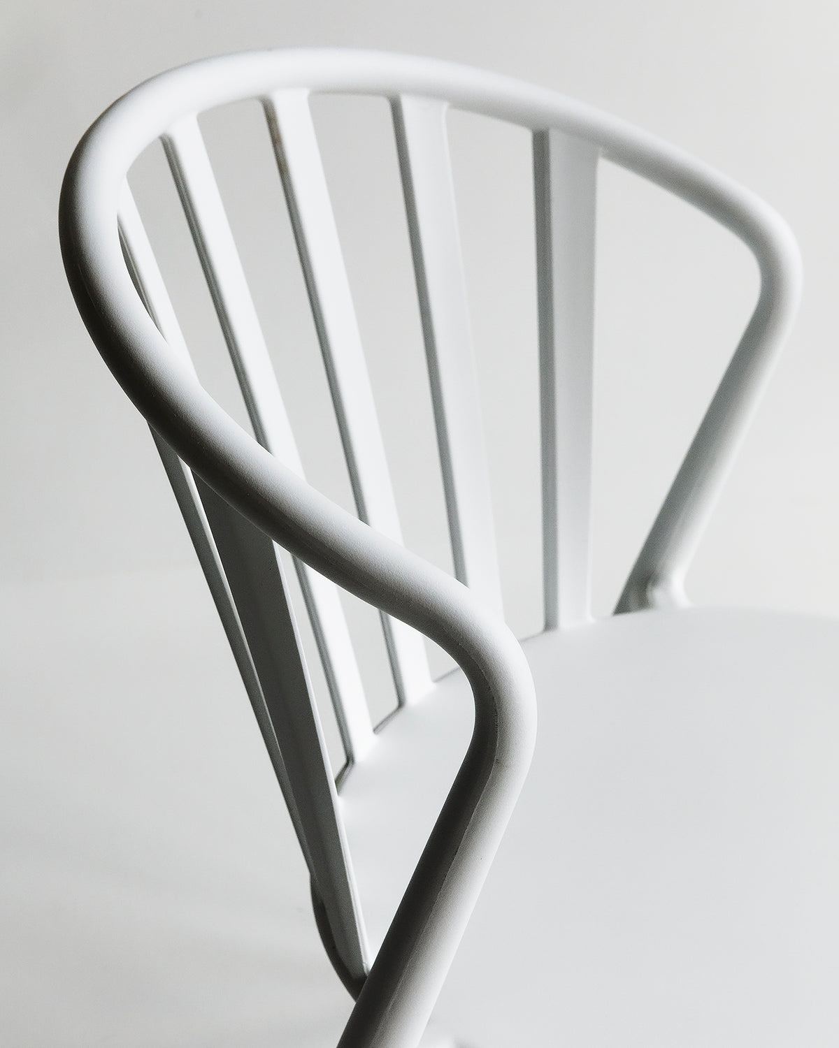 Side-angled studio view of the white Cleo chair with soft curves and lightweight frame