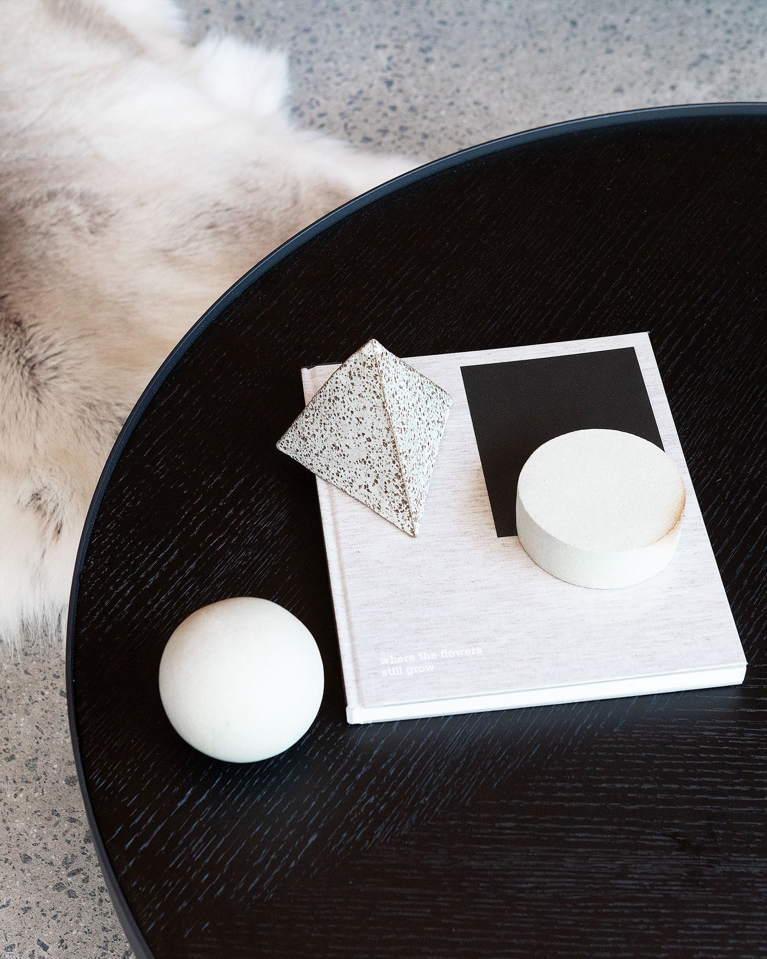 Styled top-down view of Sia Round Nesting Table in black, showing deep etched veneer and minimalist decor