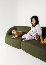 Calvin modular lounge in olive upholstery with person and dog relaxing in a styled living room