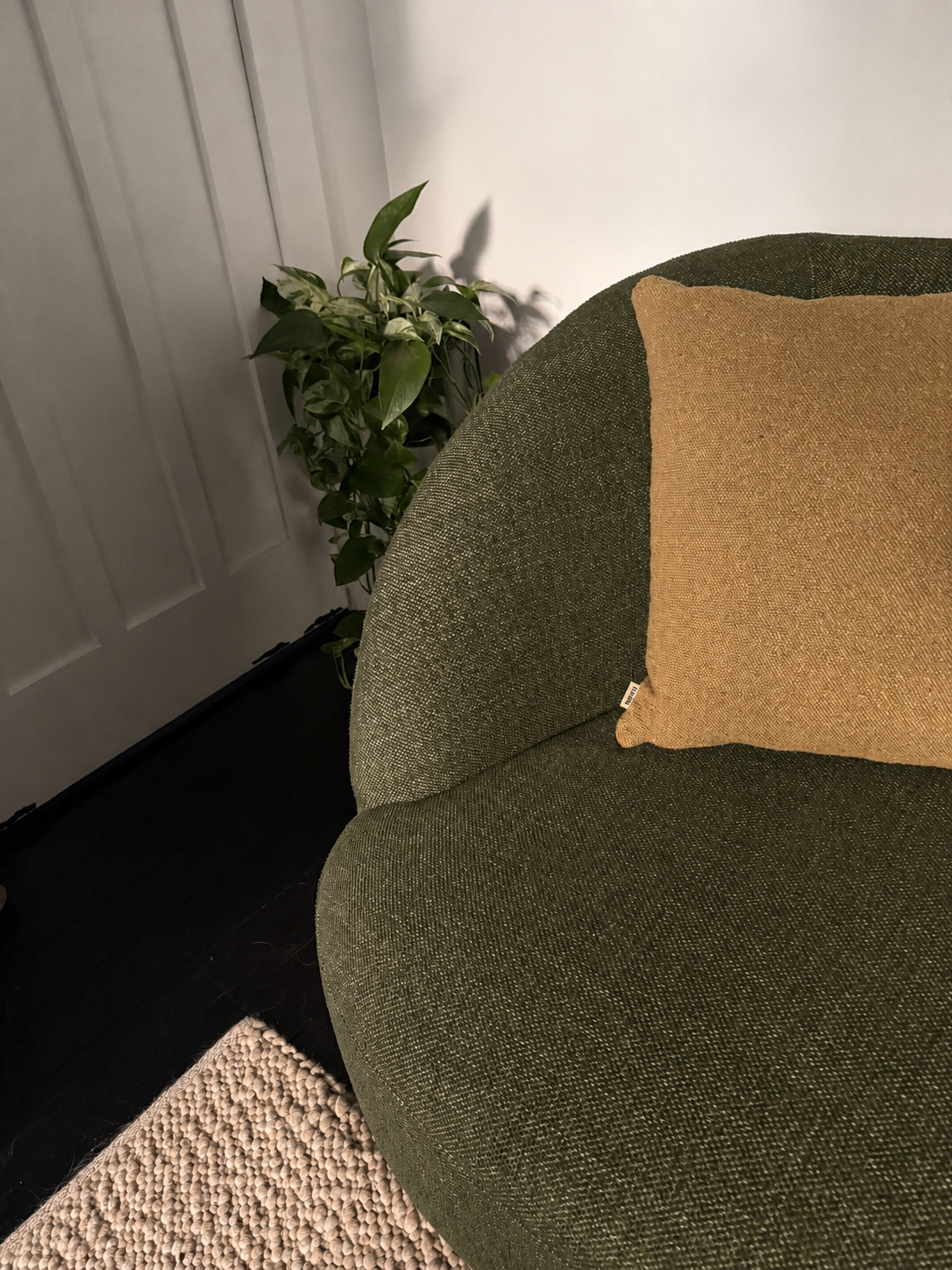 Calvin Sofa in Rove olive styled with a brick cushion against a white wall