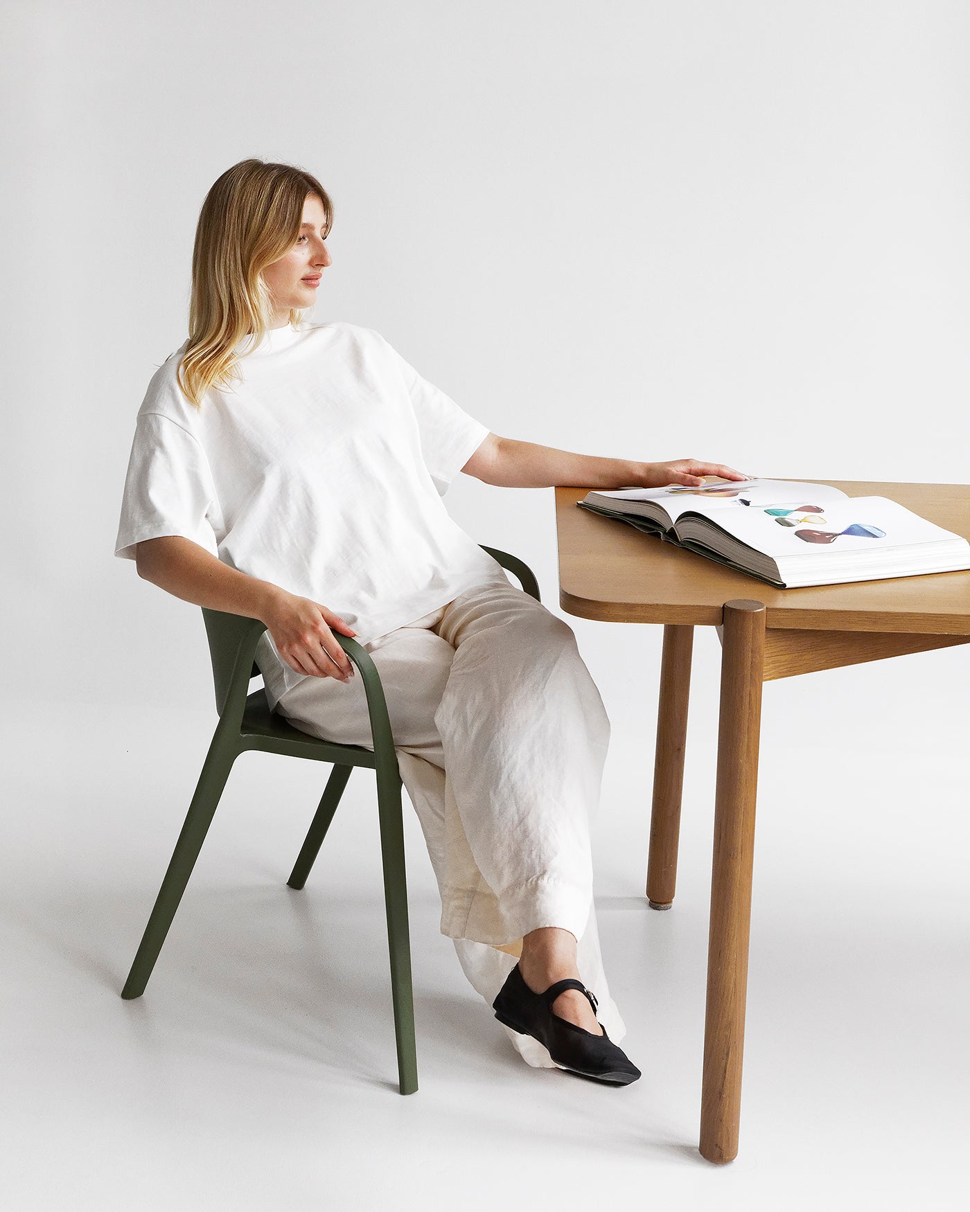 Person seated on the Olive Carla Armchair in an outdoor setting, highlighting comfort and versatility for everyday use