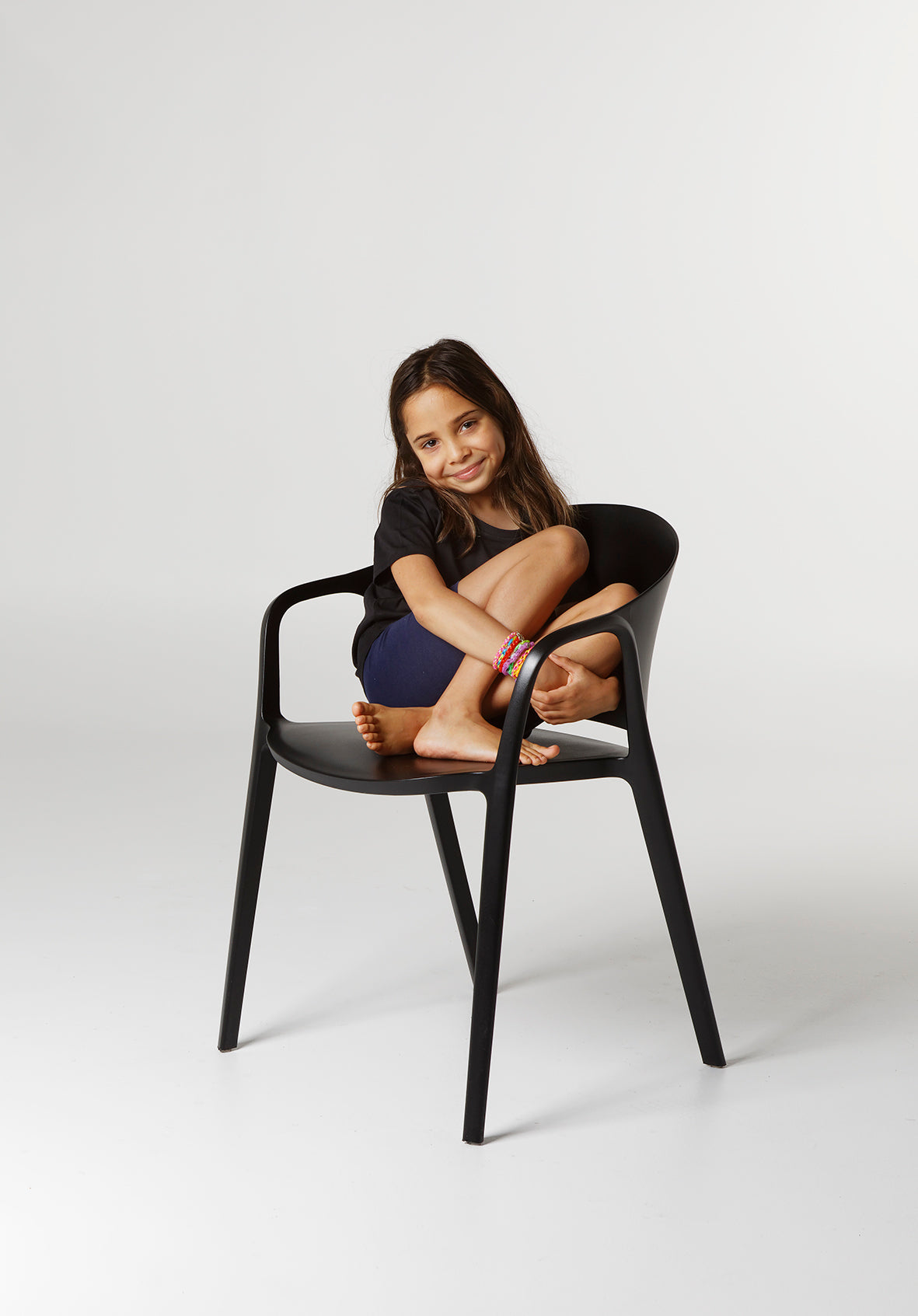 Child sitting on the Carla Chair in Black, showing its sturdy, family-friendly design and comfort for everyday indoor or outdoor use.