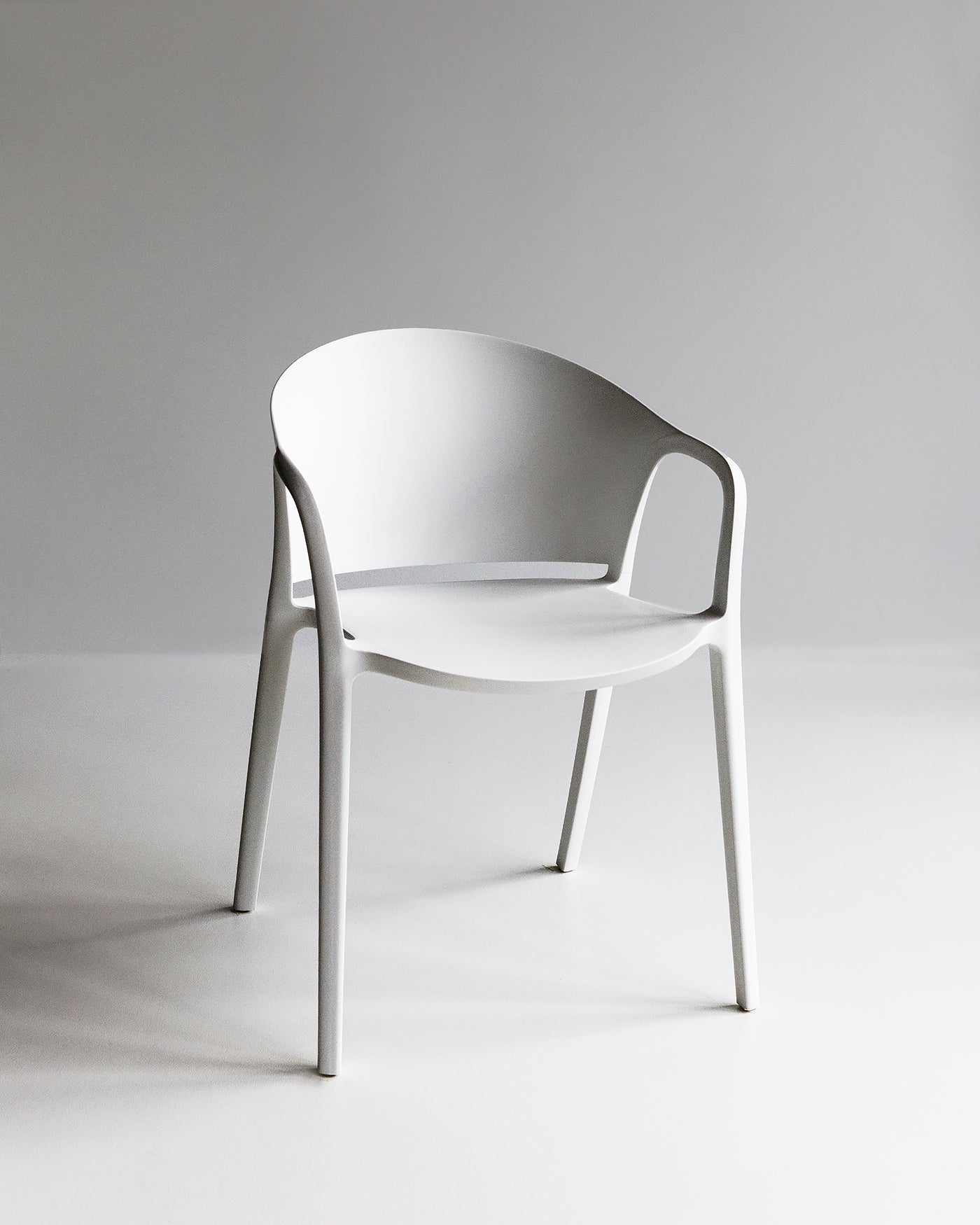 White Carla Chair shown in a minimal studio setting, highlighting its clean lines and bright matte finish.
