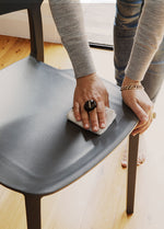 Close-up of the Charcoal Alex Chair being wiped clean with a cloth, highlighting its smooth plastic surface and low-maintenance design for busy households.