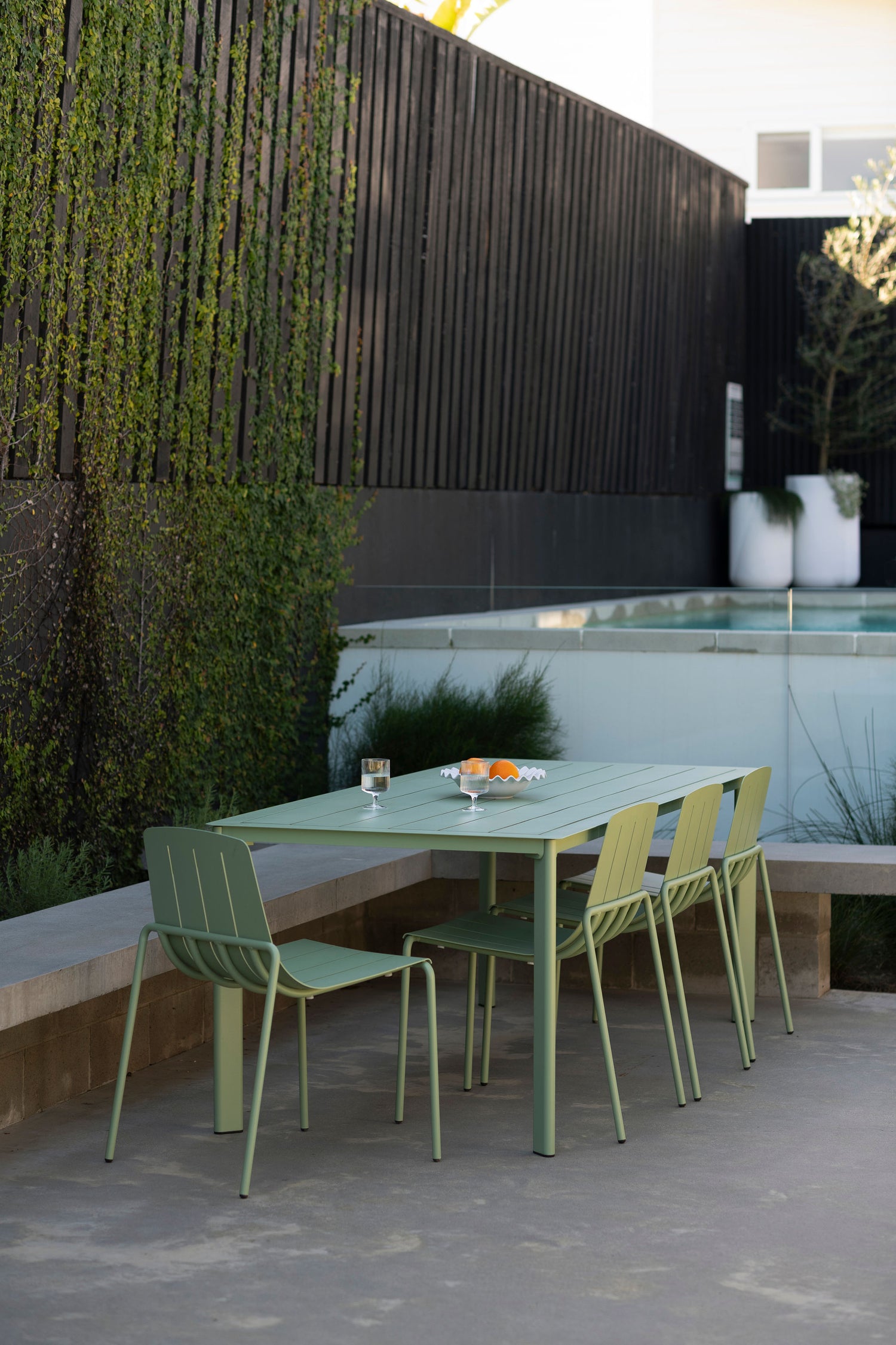 Green outdoor dining set with table and chairs on a patio.