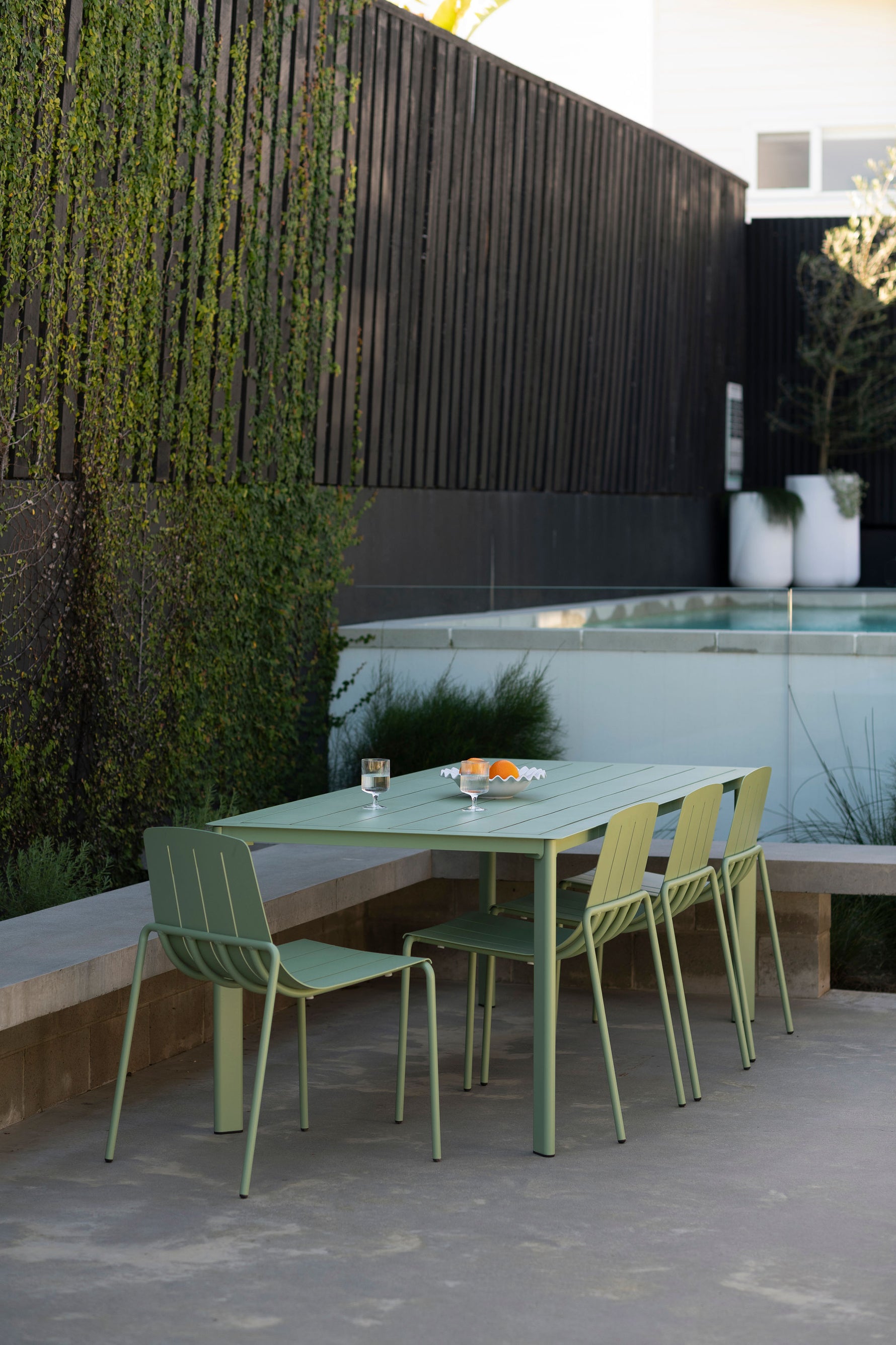Green outdoor dining set with table and chairs on a patio.