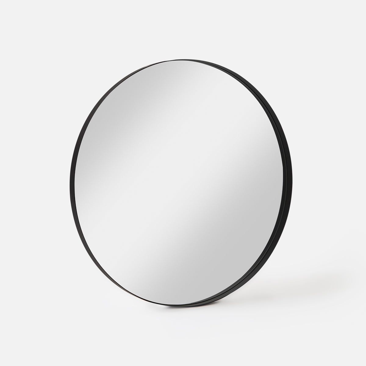 Bobbi Round Mirror in black shown at an angle, showing the depth of its frame