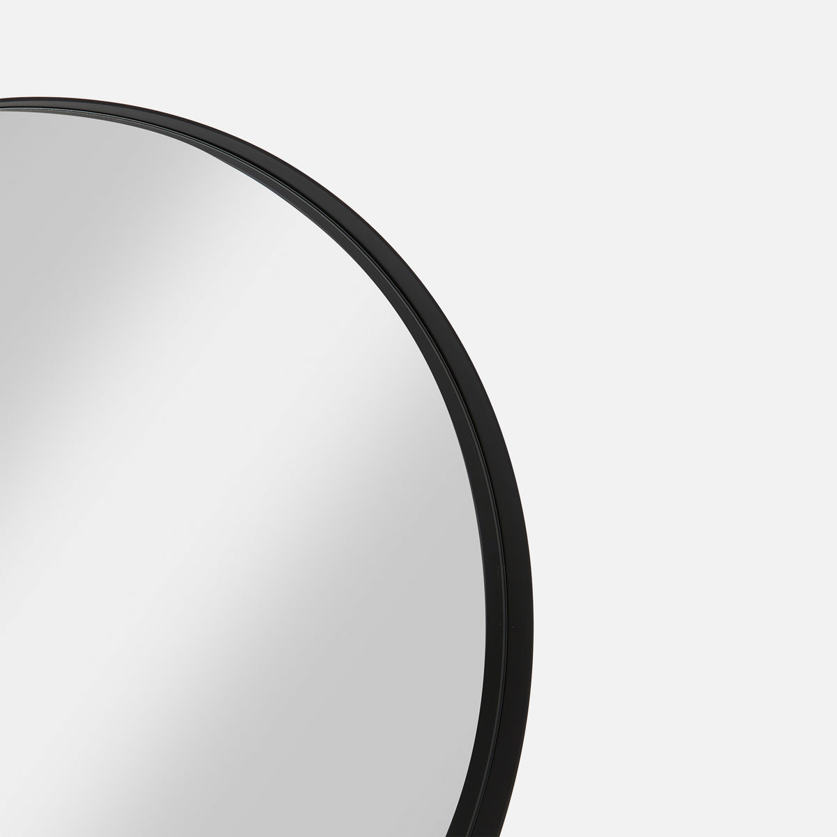 Close-up of the Bobbi Round Mirror in black, showing its slim metal frame