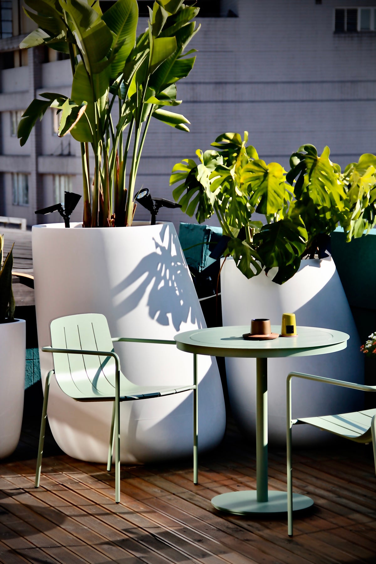 Remy Outdoor Dining Armchair in eucalypt green paired with a modern outdoor dining table, perfect for alfresco dining.