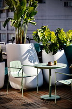 Remy Outdoor Dining Armchair in eucalypt green paired with a modern outdoor dining table, perfect for alfresco dining.