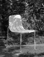 White chair in a garden setting with trees and grass