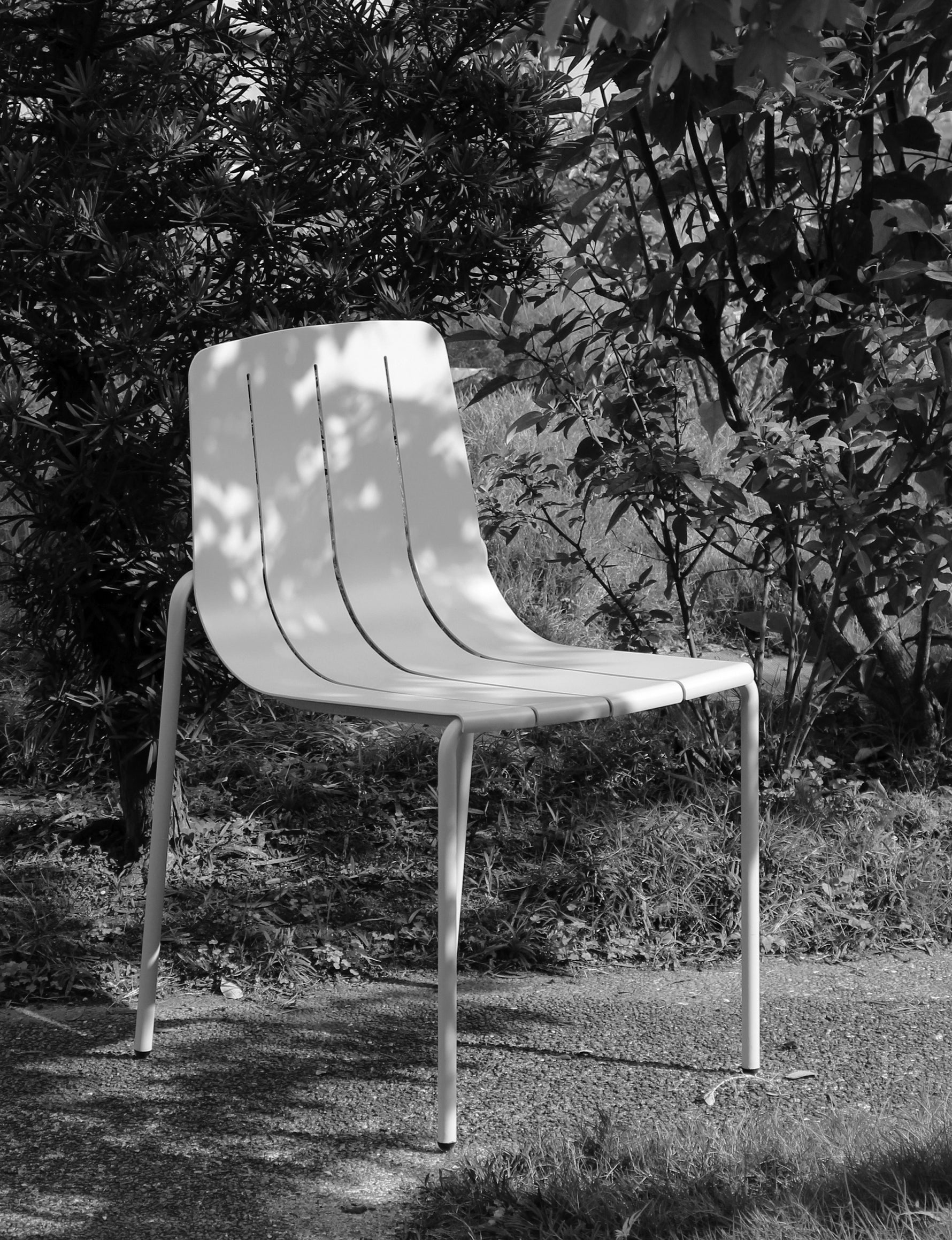 White chair in a garden setting with trees and grass