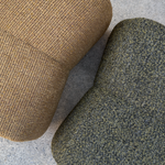 Two textured fabric chairs on a stone surface, one in warm tan and one in dark olive-gray speckled wool.