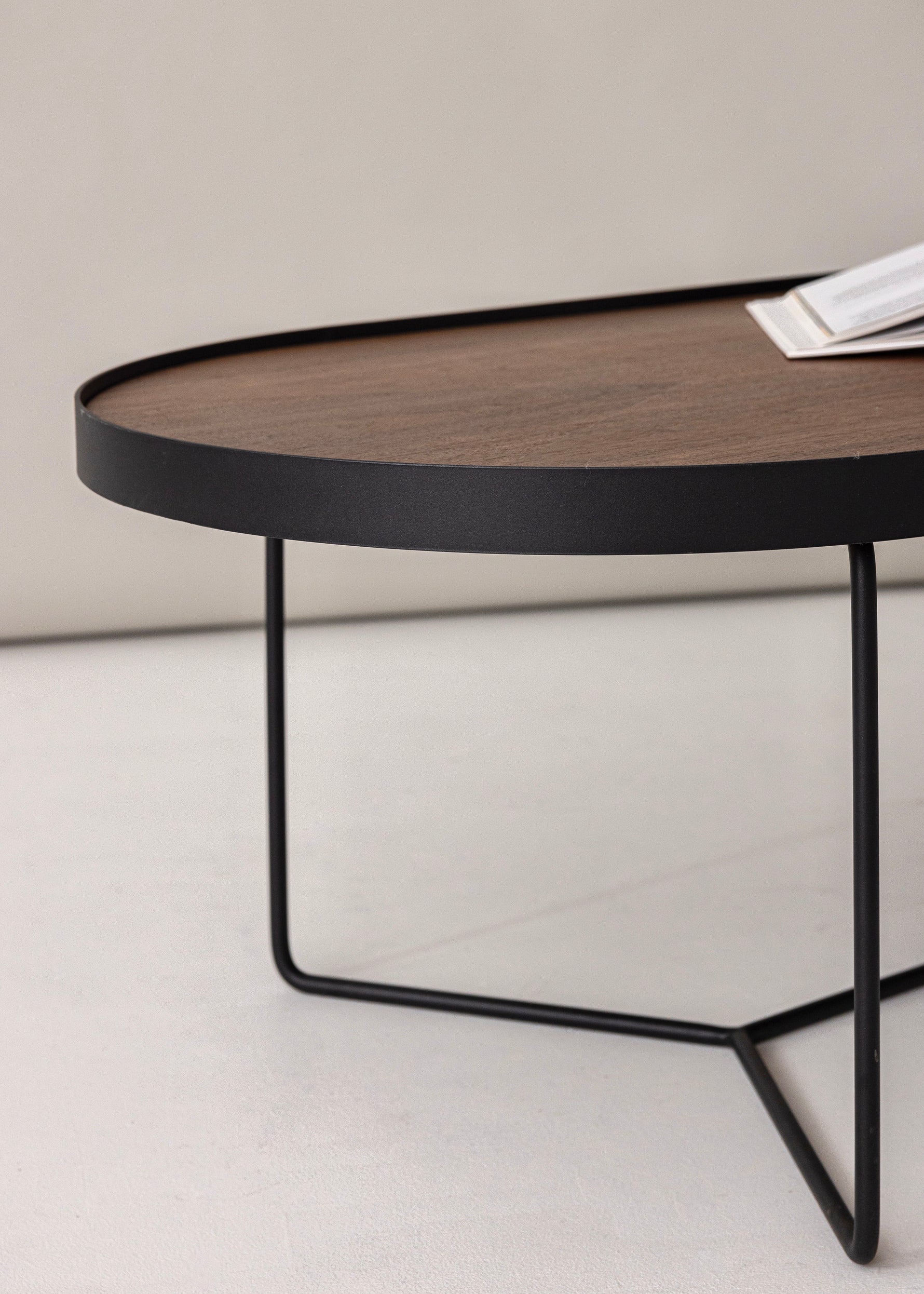 Side angle view of the Sia Oval Table in Walnut, styled in a studio setting with focus on curved edges and clean lines