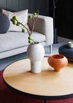 Sia round oak coffee table with deep etched top, styled in a contemporary architectural living space