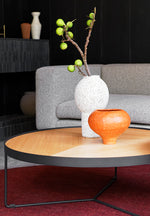 Sia round oak coffee table with deep etched top, styled in a light-filled interior with flowers in a vase