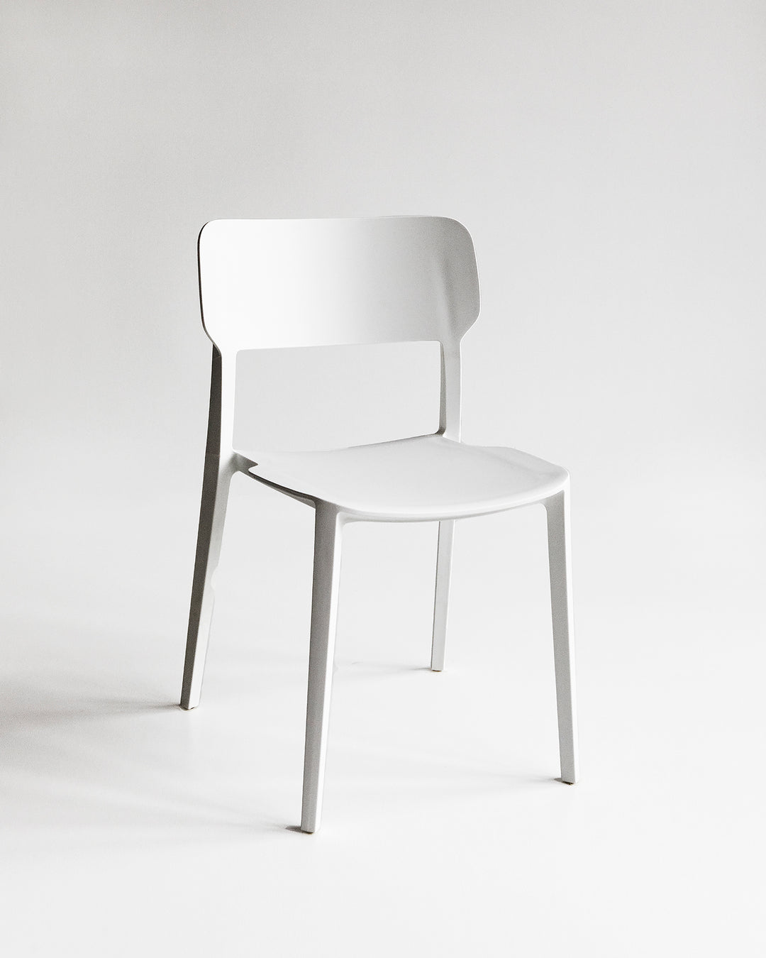 Front view of the White Alex Chair, a plastic indoor outdoor dining chair with clean lines and a contoured backrest.