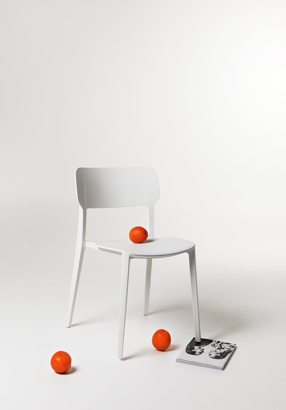 White Alex Chair styled in a clean studio setting with minimal props, showcasing its modern silhouette and fresh matte finish in a design-led composition.