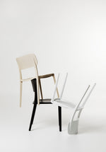 White Alex Chairs stacked in a playful, sculptural arrangement, showcasing their lightweight design and bold silhouette in a styled studio setting.