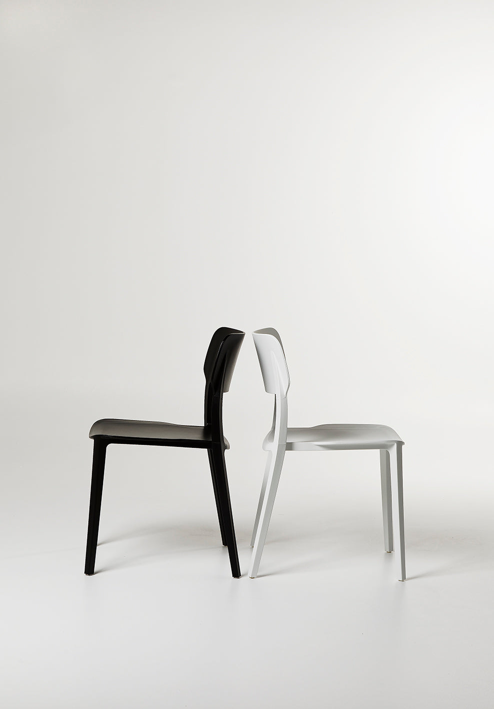 Side view of the Alex Chair in Black and White streamlined silhouette with contoured back and sturdy plastic frame.