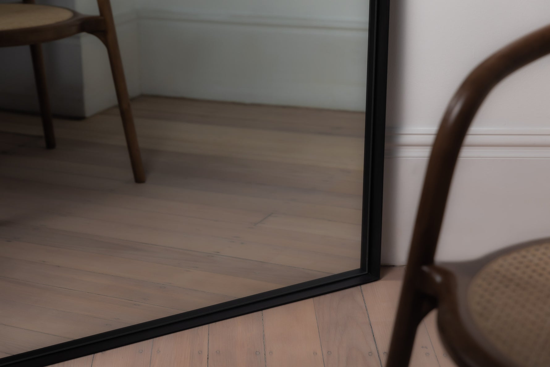 Close-up of black Archie Arch Mirror frame with recessed metal edge