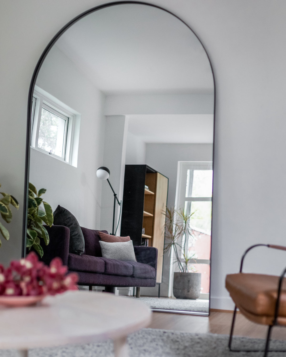 Archie Oversized Mirror in black leaning against a wall in a living room setting