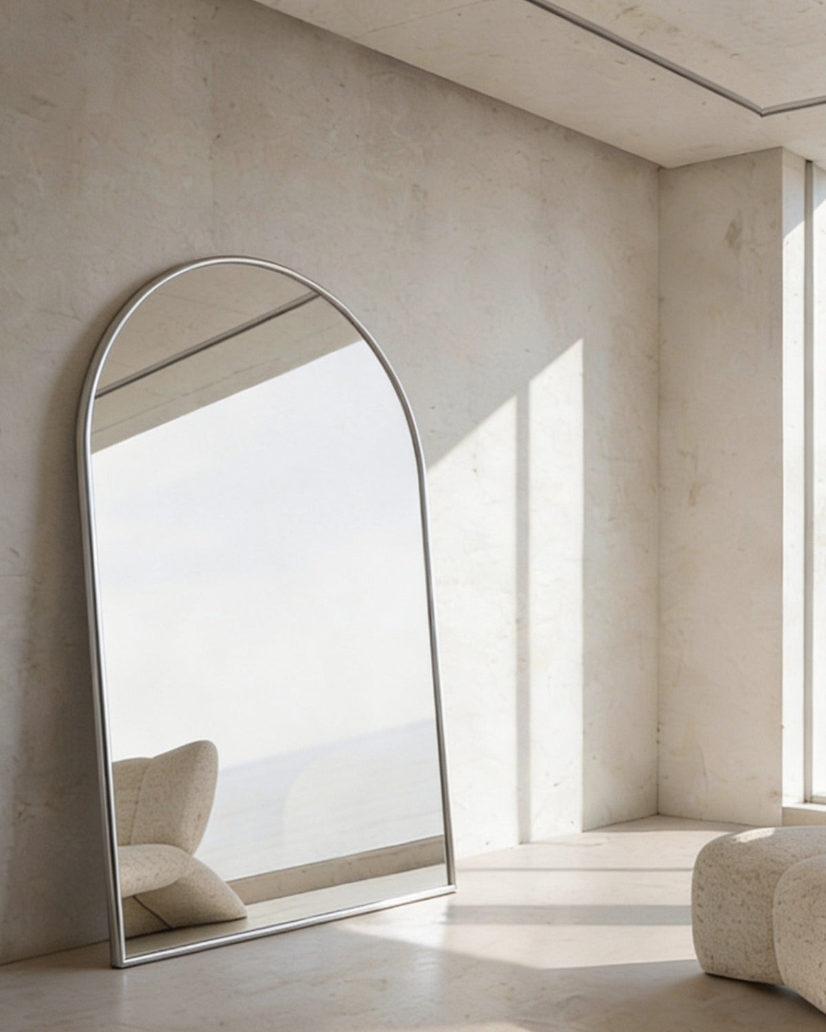 Archie Oversized Mirror in white leaning in a sunlit limewashed room beside a boucle chair