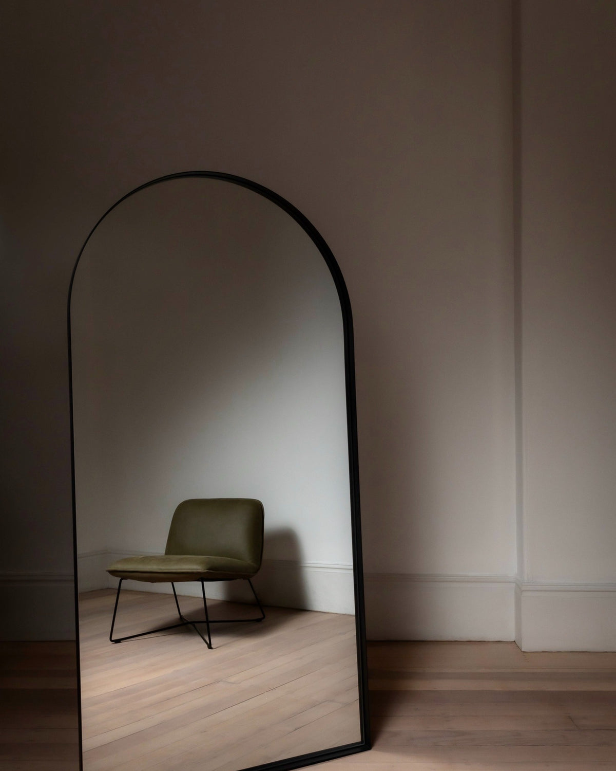 Archie Standard Mirror in black leaning in a bright empty room with pale timber floors