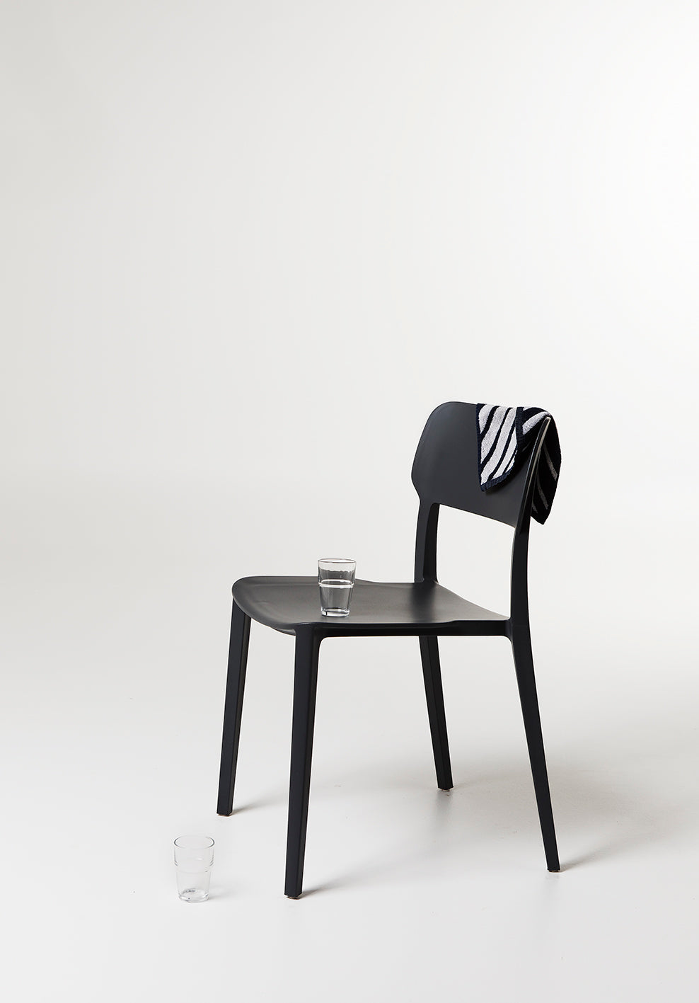 Side view of the Alex Chair in Black – streamlined silhouette with contoured back and sturdy plastic frame.
