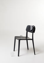Side view of the Alex Chair in Black – streamlined silhouette with contoured back and sturdy plastic frame.