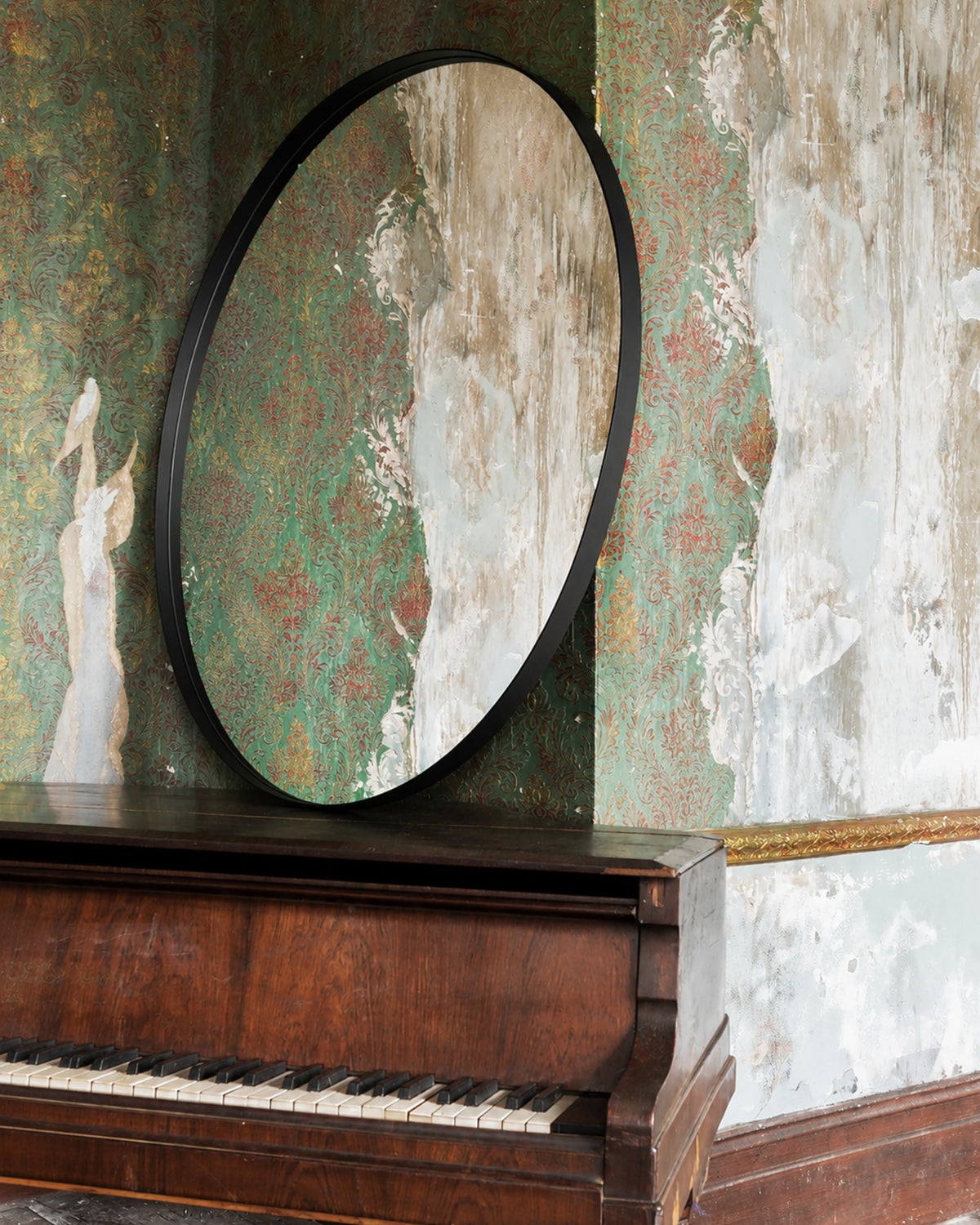 Bobbi Round Mirror in black styled in a heritage room beside a grand piano