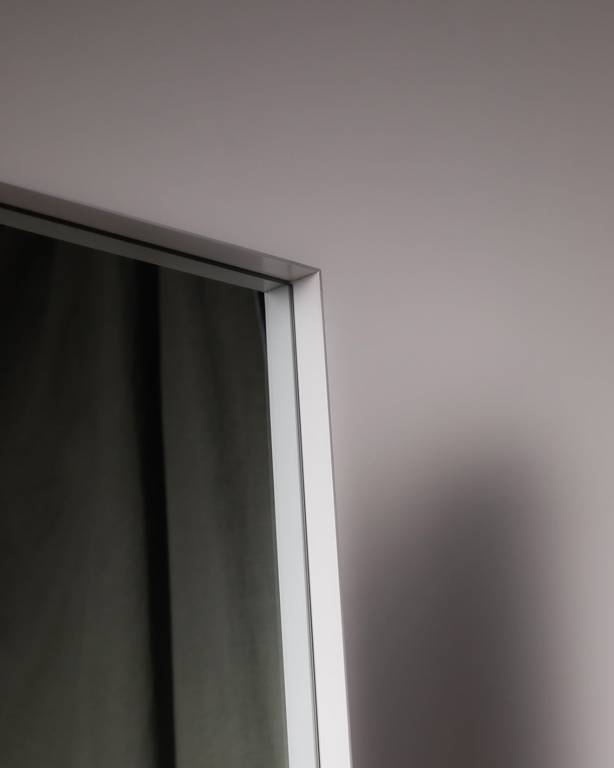 Frame detail of the Luca Standard Mirror in white, showing its slim metal profile